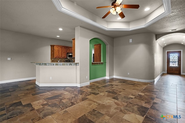 interior space featuring ceiling fan, a textured ceiling, and a raised ceiling