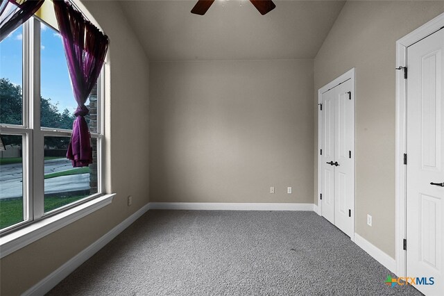 interior space featuring carpet floors, vaulted ceiling, ceiling fan, and plenty of natural light