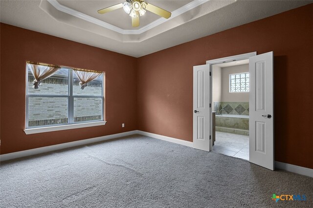 unfurnished room with ceiling fan, carpet flooring, crown molding, and a tray ceiling