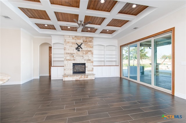 unfurnished living room featuring dark hardwood / wood-style floors, beam ceiling, a stone fireplace, crown molding, and coffered ceiling