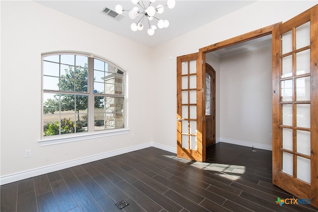 unfurnished dining area with dark hardwood / wood-style floors, an inviting chandelier, and french doors