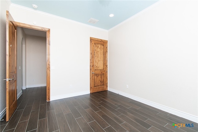 empty room with dark hardwood / wood-style floors and crown molding