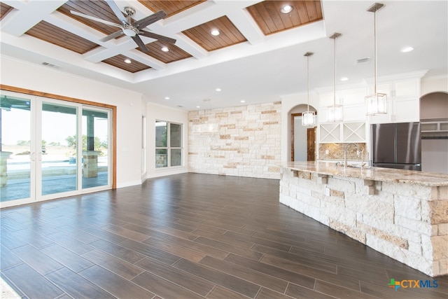 unfurnished living room featuring dark hardwood / wood-style flooring, coffered ceiling, ceiling fan, and beamed ceiling