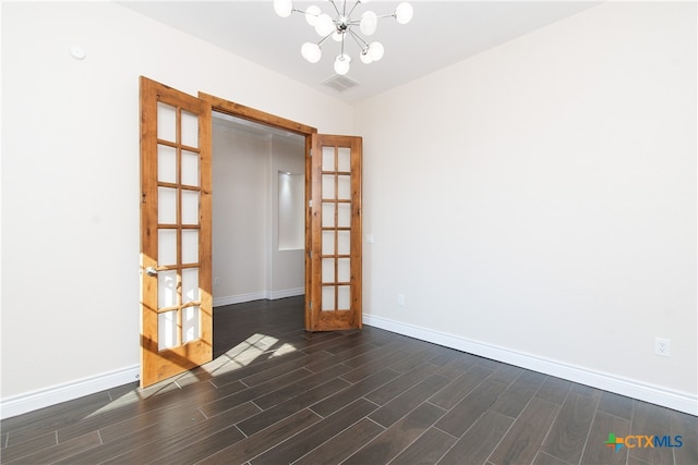 empty room featuring dark wood-type flooring and an inviting chandelier