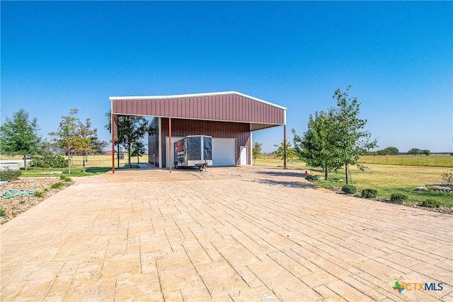 view of patio / terrace featuring an outbuilding, a garage, and a carport