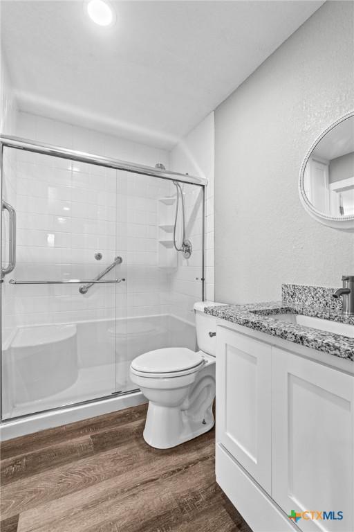 full bathroom with vanity, wood finished floors, toilet, and a shower stall