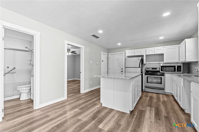 kitchen with visible vents, wood finished floors, a center island, and stainless steel appliances