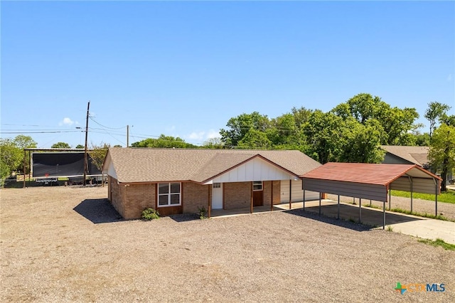 ranch-style home featuring brick siding, a detached carport, and dirt driveway