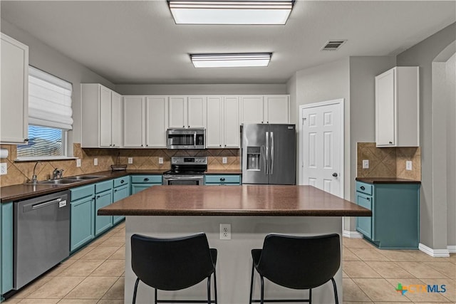 kitchen with dark countertops, visible vents, appliances with stainless steel finishes, and a breakfast bar area