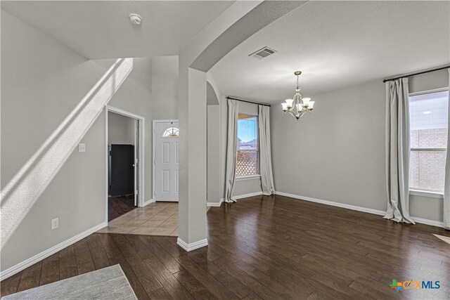 interior space featuring a chandelier, arched walkways, visible vents, and plenty of natural light
