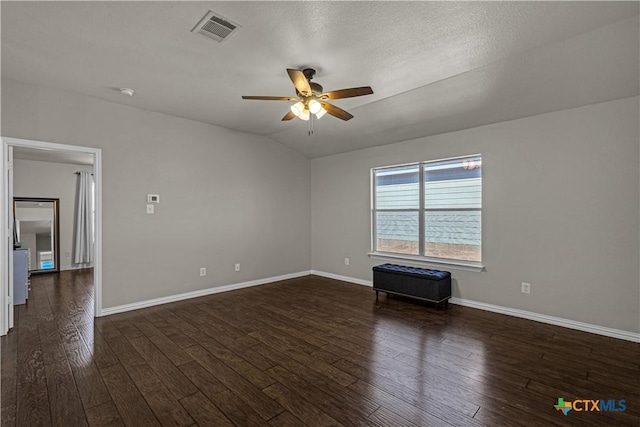 spare room featuring a ceiling fan, visible vents, dark wood-style flooring, lofted ceiling, and baseboards
