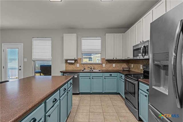 kitchen with stainless steel appliances, white cabinets, blue cabinetry, and dark countertops