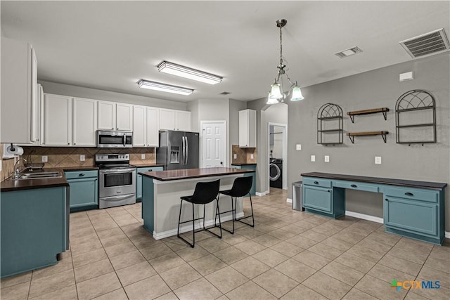 kitchen with dark countertops, visible vents, appliances with stainless steel finishes, and a sink