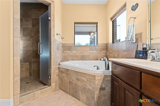 full bath with plenty of natural light, a stall shower, a garden tub, vanity, and tile walls