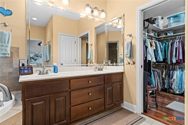 full bathroom with double vanity, a spacious closet, tile patterned flooring, and tiled shower