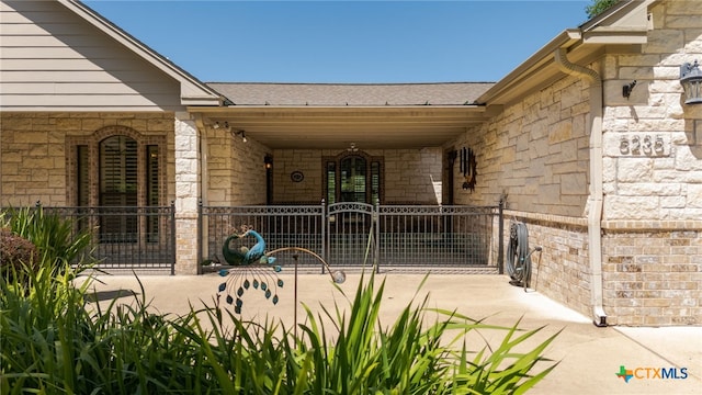 doorway to property with stone siding, a porch, a shingled roof, and a gate