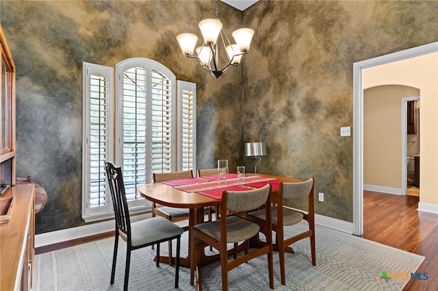 dining room with wood finished floors, baseboards, plenty of natural light, and arched walkways