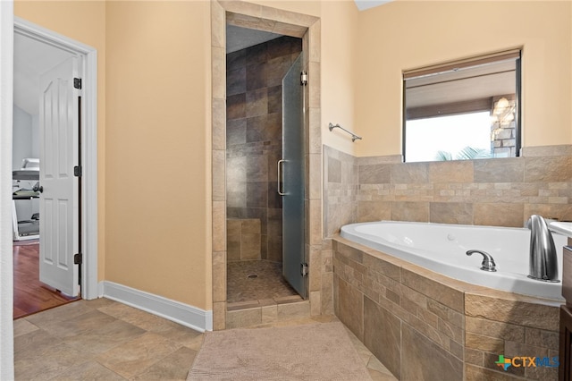 bathroom featuring a stall shower, a garden tub, and baseboards