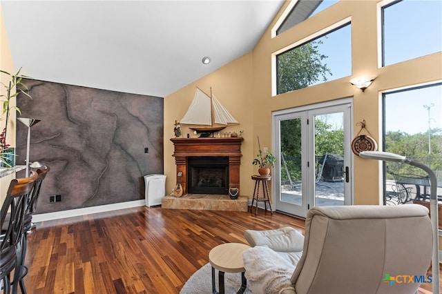 living room featuring wood finished floors, a fireplace with raised hearth, high vaulted ceiling, and baseboards