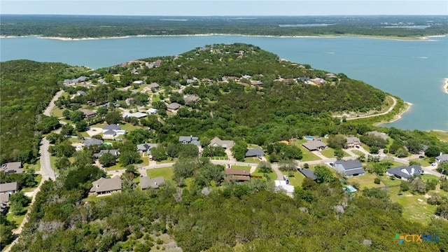 view of property location with a nearby body of water, nearby suburban area, and a heavily wooded area