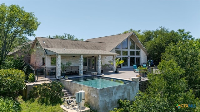 back of property with stone siding, ceiling fan, an outdoor pool, roof with shingles, and a patio area