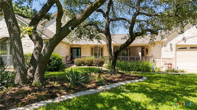 single story home with stone siding, an attached garage, a front yard, and covered porch