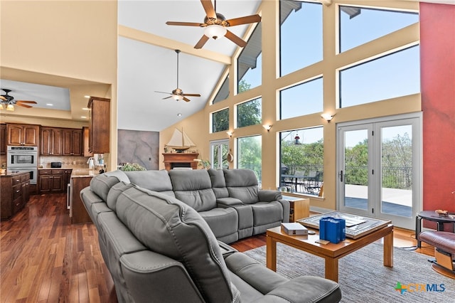 living area with a ceiling fan, high vaulted ceiling, dark wood-style flooring, and beamed ceiling