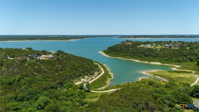 drone / aerial view of a nearby body of water and a heavily wooded area