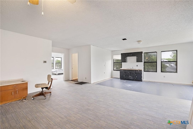 unfurnished living room with plenty of natural light, a textured ceiling, and baseboards
