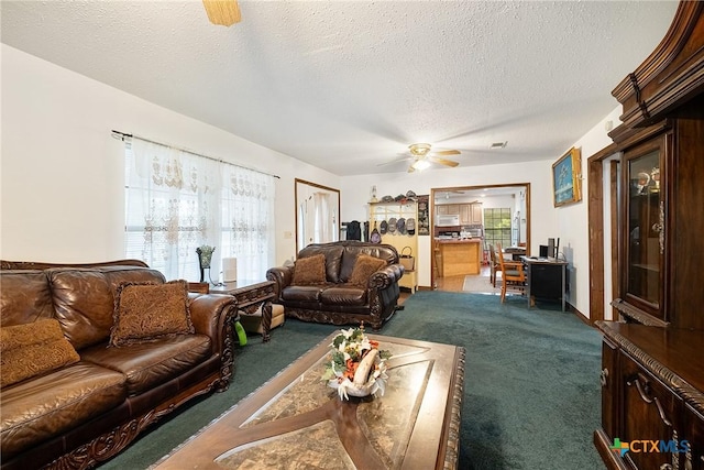 carpeted living room with healthy amount of natural light, a textured ceiling, and a ceiling fan