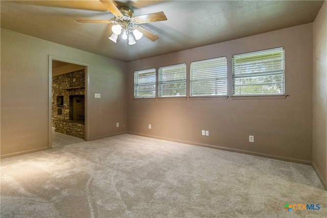 carpeted spare room with a fireplace, ceiling fan, plenty of natural light, and a textured ceiling