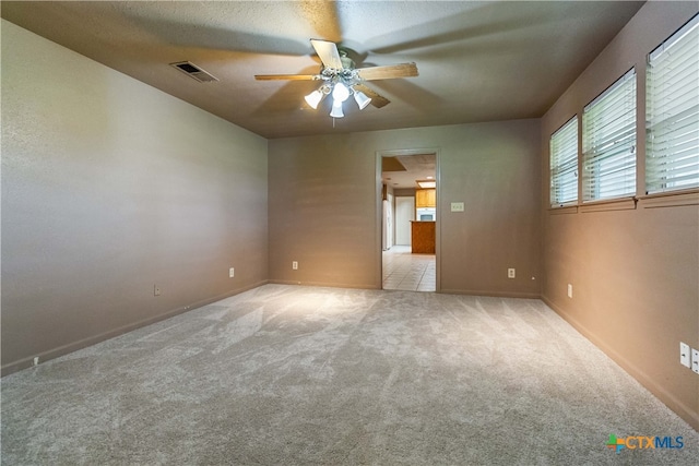 empty room featuring ceiling fan, light colored carpet, and a textured ceiling