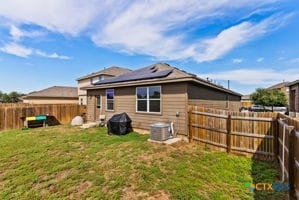 back of house featuring central AC unit and a yard