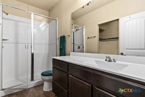 bathroom featuring walk in shower, vanity, and toilet