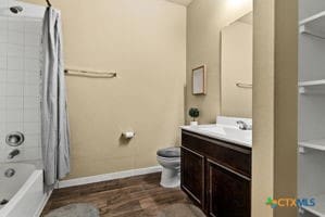 full bathroom featuring toilet, vanity, shower / bath combo with shower curtain, and hardwood / wood-style flooring