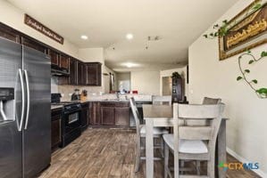 kitchen featuring hardwood / wood-style flooring, kitchen peninsula, dark brown cabinets, stainless steel fridge with ice dispenser, and electric range