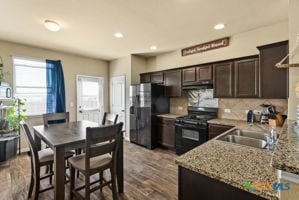 kitchen featuring sink, black appliances, light stone counters, hardwood / wood-style floors, and dark brown cabinets