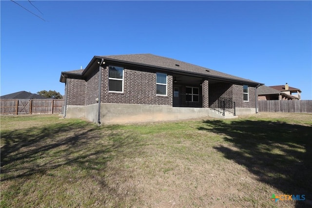 back of property featuring a yard, brick siding, a patio area, and a fenced backyard