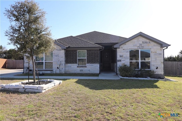 ranch-style home featuring a shingled roof, stone siding, fence, and a front lawn