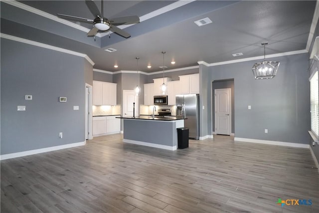 kitchen with light wood finished floors, dark countertops, appliances with stainless steel finishes, open floor plan, and ceiling fan with notable chandelier