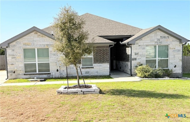 back of property with roof with shingles, fence, and a yard