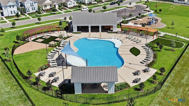 view of swimming pool with fence, a lawn, and a residential view