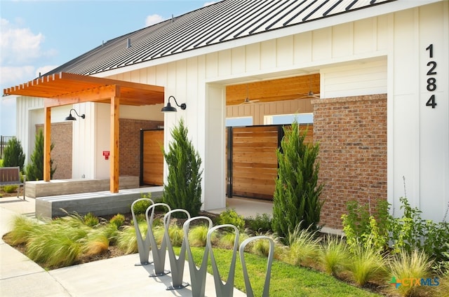 doorway to property with covered porch, brick siding, a standing seam roof, and metal roof