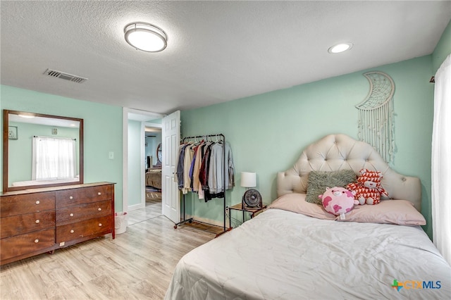 bedroom featuring light hardwood / wood-style floors and a textured ceiling