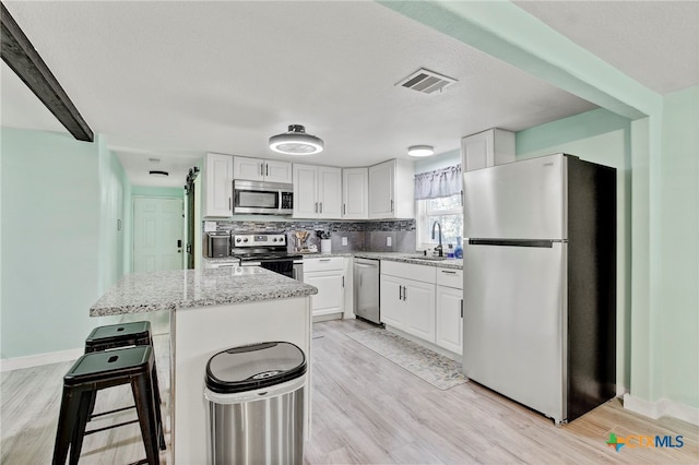 kitchen with sink, white cabinets, stainless steel appliances, and light hardwood / wood-style floors