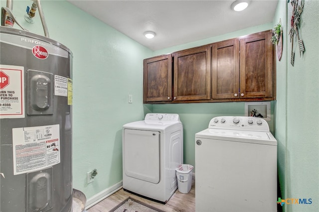 laundry area with light hardwood / wood-style floors, cabinets, independent washer and dryer, and water heater