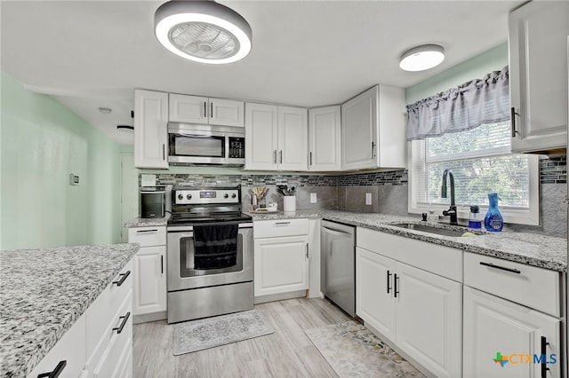 kitchen featuring light stone countertops, appliances with stainless steel finishes, tasteful backsplash, sink, and white cabinets