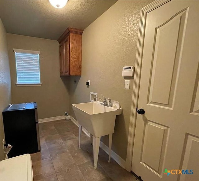 laundry room featuring baseboards, hookup for a washing machine, a textured wall, electric dryer hookup, and a textured ceiling