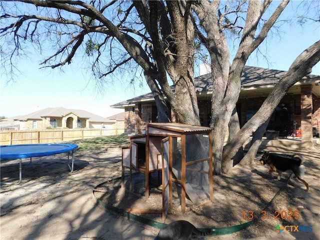 exterior space with exterior structure, a trampoline, and fence