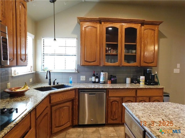 kitchen featuring a sink, dishwasher, brown cabinetry, and vaulted ceiling